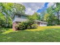 Two-story home with a lush green lawn, mature trees, and partial brick exterior, offering classic curb appeal at 1956 Joseph Ct, Decatur, GA 30032