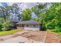Exterior view of a house with light siding, brick accents, a driveway, and mature trees at 1956 Joseph Ct, Decatur, GA 30032