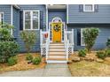Close-up of a vibrant yellow front door adorned with a wreath, framed by white railings and manicured landscaping at 7660 Brentwood Ct, Cumming, GA 30040