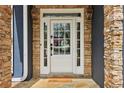 Close up of front door with stone surround, glass panel and sidelights, and exterior wall lanterns at 2305 Stonevalley Ct, Cumming, GA 30041