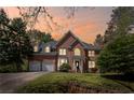 Charming brick home featuring a manicured lawn, arched entry, and attached two-car garage at dusk at 5628 Fallsbrook Nw Knl, Acworth, GA 30101