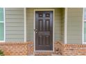 Close-up of a dark wooden front door with sidelights, brick trim, and modern hardware at 1800 Pearson St, Loganville, GA 30052