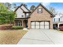 Inviting two-story brick home with a long driveway and an attached two-car garage at 2172 Misty Brook Ct, Buford, GA 30519