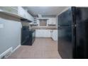 An older kitchen features a black refrigerator, stove, white cabinets, and tiled floors, offering a functional space at 1753 Thomas Ter, Decatur, GA 30032