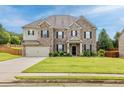 Inviting two-story home with a green lawn, a brick facade, and a spacious two-car garage at 312 Amble Side, Mcdonough, GA 30252