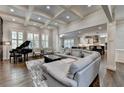 Open-concept living room featuring coffered ceilings, hardwood floors, and large windows, with a view to the kitchen at 7940 Royal Melbourne Way, Duluth, GA 30097