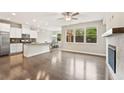 Open-concept living room with hardwood floors, fireplace, and a modern kitchen with stainless steel appliances at 207 Magnolia Creek Way, Woodstock, GA 30188