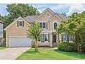 Charming two-story traditional home with tan siding, an attached garage and a well-manicured lawn at 1780 Riverglen Dr, Suwanee, GA 30024