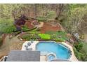 Aerial view showcases a beautiful pool, lush landscaping, and firepit, creating a private outdoor oasis at 3520 Millwater Xing, Dacula, GA 30019
