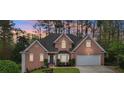 Inviting two-story red brick home featuring a well-manicured lawn, bay window, and attached two-car garage at 740 Trillium Ln, Lilburn, GA 30047