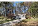 Single-story home with two-car garage, a well-kept lawn, a long driveway, and a wooded backdrop at 90 Chimney Rise Ct, Stockbridge, GA 30281