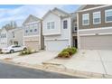 Three neutral colored townhomes each featuring a single car garage and driveway at 6179 Centennial Run, Atlanta, GA 30349
