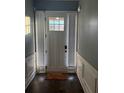 Bright foyer features a door with sidelights, dark wood flooring, and wainscotting at 227 Shellbark Dr, Mcdonough, GA 30252