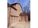 Three-car garage with traditional doors and brick exterior, offering ample parking and storage at 227 Shellbark Dr, Mcdonough, GA 30252