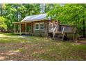 Charming log cabin featuring a side deck and a stone foundation, surrounded by lush greenery at 1615 Hilltop Ct, Woodstock, GA 30188