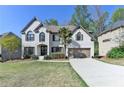 Traditional white brick home featuring a lush front lawn, complemented by a paved driveway and a two-car garage at 6770 Ulster Ct, Alpharetta, GA 30005