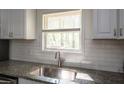 Close up of kitchen featuring granite countertops, stainless steel sink, subway tile backsplash, and white cabinets at 4704 Apache Sw Trl, Atlanta, GA 30331