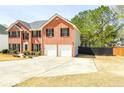 Side view of two-story brick home featuring an attached two-car garage and large driveway at 3903 Cain Mill Dr, Lithonia, GA 30038