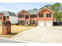 Two-story brick home featuring an attached two-car garage, landscaping, and large driveway at 3903 Cain Mill Dr, Lithonia, GA 30038