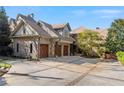 Stone home featuring a large driveway leading to a spacious three-car garage with wooden doors at 6316 Woodlake Dr, Buford, GA 30518