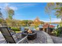 Stone patio with fire pit overlooking the lake, surrounded by mature trees and lush landscaping at 6316 Woodlake Dr, Buford, GA 30518