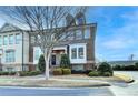 Brick townhome featuring manicured landscaping, a covered entrance, and symmetrical shrubbery at 4323 Tacoma Trce, Suwanee, GA 30024