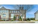 Multiple townhomes featuring brick exteriors, symmetrical landscaping, and covered entrances on a sunny day at 4323 Tacoma Trce, Suwanee, GA 30024