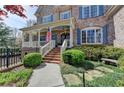 Charming brick home featuring a covered front porch, American flag, and manicured landscaping at 2510 Bent Creek Way, Cumming, GA 30041