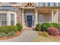 Inviting front entrance with a navy blue door, stone accents, and lush landscaping at 5808 Deer Crossing Dr, Sugar Hill, GA 30518