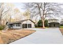 Exterior view of the home featuring a two-car garage, large driveway, and an extra storage building at 2923 Glenhaven Sw Ct, Conyers, GA 30094