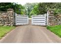 A stone and wood entrance gate leads to a private estate drive surrounded by mature trees at 2100 West Wesley Rd, Atlanta, GA 30327