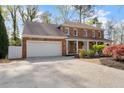 A well-maintained two-story brick home featuring an attached garage and manicured landscaping at 3824 Running Fox Dr, Marietta, GA 30062