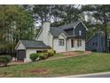Charming white brick home with a dark garage door, well-maintained landscaping, and a brick pathway at 2048 Kelvin Dr, Lawrenceville, GA 30043