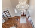 Upper view of the foyer with beautiful chandelier, hardwood floors, staircase and entry doors at 5394 Brendlynn Dr, Suwanee, GA 30024