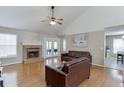 Bright living room featuring hardwood floors, vaulted ceiling, and a cozy brick fireplace at 1545 Smoke Hill Dr, Hoschton, GA 30548
