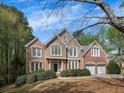 Beautiful two-story home featuring a mix of brick and stucco exterior, lush landscaping, and a driveway at 11770 Ashwick Pl, Johns Creek, GA 30005