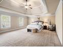 Spacious main bedroom featuring a tray ceiling, plush carpet, and abundant natural light at 1526 Rocky River Dr, Lawrenceville, GA 30045