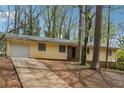 Single-story home with a attached garage, a brick foundation, and a long driveway at 1360 Cypress Ridge Cir, Stone Mountain, GA 30083