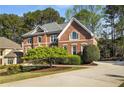 Brick home featuring manicured landscaping, a curved driveway, and lush greenery surrounding the property at 3060 Birchton St, Johns Creek, GA 30022