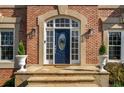 Close-up of the blue front door, framed by sidelights, stone steps, and decorative potted plants at 3060 Birchton St, Johns Creek, GA 30022
