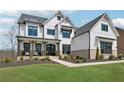 Beautiful two-story home featuring white siding, black trim windows and covered porch at 13415 Bishops Ct, Roswell, GA 30075