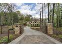 Gated driveway leading to a luxurious home, surrounded by lush greenery and mature trees at 3451 Paces Ferry Nw Rd, Atlanta, GA 30327