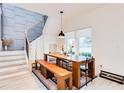 Bright dining area with a large wooden table, bench seating, modern light fixture, and stylish staircase at 1506 Avon Sw Ave, Atlanta, GA 30311