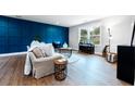 Comfortable living room with a striking blue accent wall, stylish furnishings, and wood grain flooring at 5747 S Gordon Rd, Austell, GA 30168