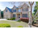 Beautiful two-story brick home with a manicured lawn, two-car garage, and mature trees in a suburban setting at 4880 Stone Moss Path, Hoschton, GA 30548