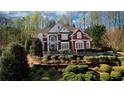 Two-story brick home with a front porch and lush landscaping surrounded by mature trees, offering privacy at 4777 Ardmore Ln, Hoschton, GA 30548
