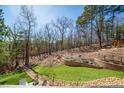 Landscaped backyard featuring stone walls, green lawn and mature trees, offering a serene outdoor space at 139 Stargaze Rdg, Canton, GA 30114