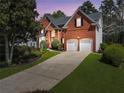 Charming two-story brick home with a well-manicured lawn and a two-car garage at dusk at 1665 Millhouse Lndg, Marietta, GA 30066