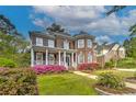 Elegant two-story brick home with a covered porch and vibrant landscaping showcasing pink flowers at 1956 Grace Arbor Ne Ct, Atlanta, GA 30329