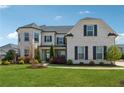 Charming two-story home with white brick, black shutters, and lush green lawn under blue sky at 214 Leland Way, Woodstock, GA 30188